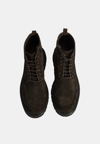 Bruine suède enkellaarsjes met vetersluiting en rits, textiel stof en rubberen zolen. Bevat stiksels en een trekstrook op de hiel.