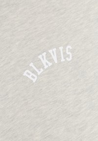 Jasnoszara tkanina z białymi, blokowymi literami zapisującymi "BLKVIS", ułożonymi w lekkim łuku na powierzchni.