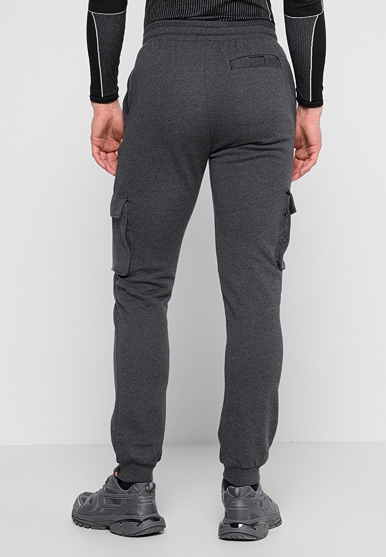 Szare bawełniane spodnie cargo z kieszeniami bocznymi, elastycznym pasem i zwężanymi kostkami. Noszone z czarnymi butami sportowymi.