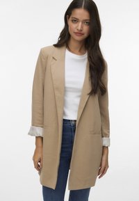 Beige bleiseri rento istuvuus, yksipainikainen kiinnitys ja kaksi etutaskua. Ominaisuuksiin kuuluu käärityt hihat, joissa on raidallinen yksityiskohta.