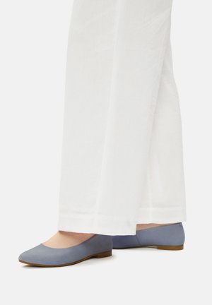 Jasnoniebieskie płaskie buty noszone z białymi spodniami o szerokich nogawkach na białym tle, przedstawiające widoki z boku i z tyłu obu stóp.