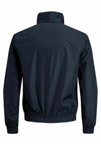 Chaqueta cortavientos azul marino con un alto cuello, puños elásticos y cintura ajustable. Material suave y ligero con un diseño simple.
