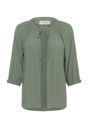 Gaiši zaļa blūze ar apaļu kakla izgriezumu, saites detaļu, 3/4 garuma piedurknēm un teksturētu centrālo paneļu, kas ar pinuma dizainu. Mīksta auduma, brīva piegriezuma.