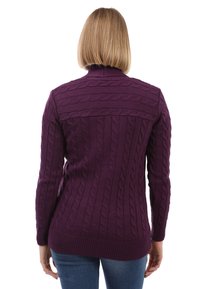 Lila Kabelstrickpullover mit langen Ärmeln, gerippten Bündchen und Saum, der ein strukturiertes Muster auf der Rückseite zeigt, getragen über blauen Jeans.