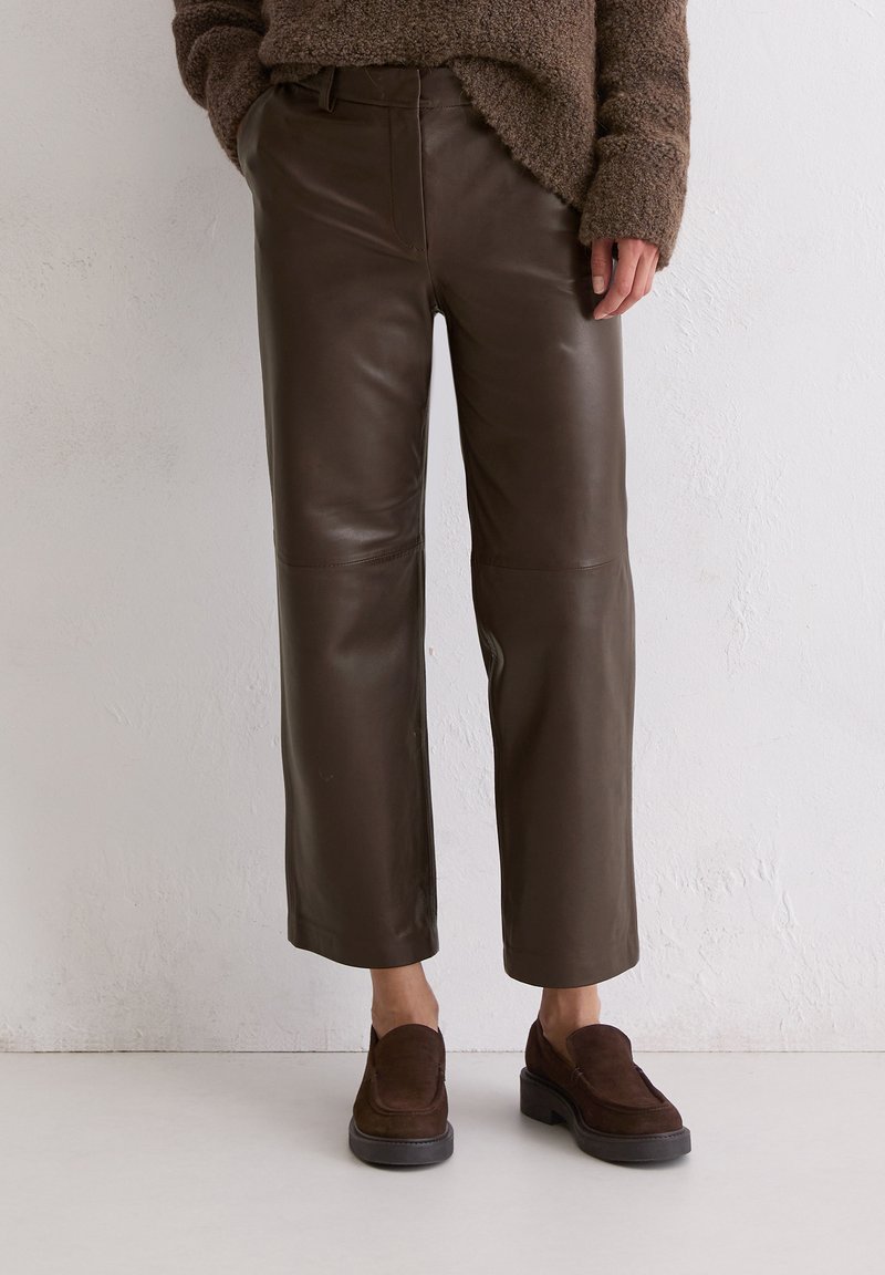 Bruine leren cropped broeken met een gladde textuur, voorzien van een hoge taille en rechte pijpen. Gecombineerd met donkerbruine suède loafers.