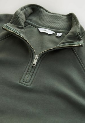 Donkergroen pullover met een hoge kraag en een half-rits sluiting. Gladde stof met geribbelde kraagdetails en een "NEXT" label aan de binnenzijde. Maat M.
