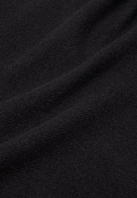 Tissu noir avec une surface douce et texturée, présentant des plis subtils et des variations de brillance ; couleur uniforme et aspect léger.