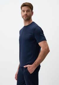 T-shirt a maniche corte blu navy con scollo rotondo, realizzato in tessuto leggero e morbido. Presenta una discreta rifinitura cucita lungo i bordi.