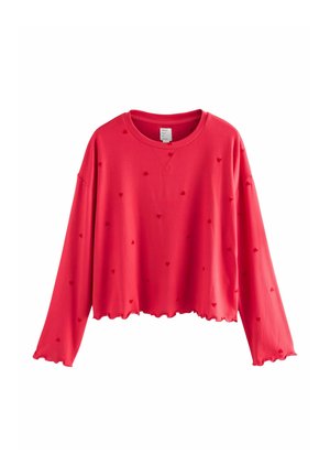 Red cropped sweatshirt with long sleeves, scalloped hem, and textured heart patterns throughout. Made from soft fabric. Label visible inside neckline.