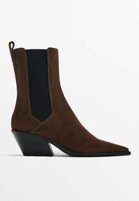Bottine en daim marron avec bout pointu, panneau latéral élastique noir, talon bloc incliné et languette à l'arrière.