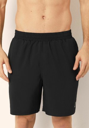 Sorte atletiske shorts med elastisk linning og en glat, let tekstur. Har et lille logo på det nederste venstre ben.