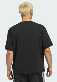 Black cotton t-shirt with a relaxed fit, short sleeves, and a round neckline; smooth texture with a plain design and no visible logos.