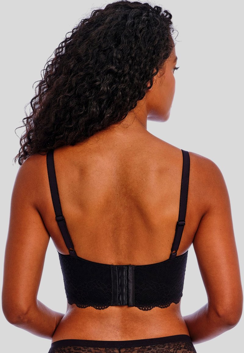 Bralette de encaje negro con tirantes ajustables, borde festoneado y cierre de gancho y ojo en la parte trasera. Textura suave y diseño minimalista.
