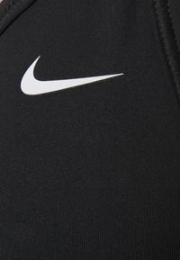 Tessuto atletico nero con una superficie liscia, caratterizzato da un logo Nike bianco. Il design è aderente con cuciture minime.