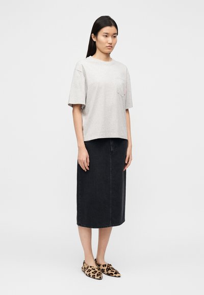 Γκρι βαμβακερό μπλουζάκι με τσέπη στο μπροστινό μέρος, συνδυασμένο με μαύρη μίντι φούστα από τζιν και φλατ παπούτσια με λεοπάρ σχέδιο. Δομημένη, casual εφαρμογή.