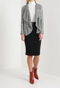 Gray and white textured cardigan over a white turtleneck, paired with a black pencil skirt and red ankle boots.