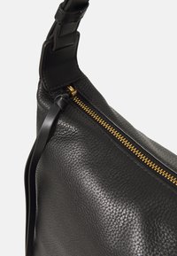 Schwarze Lederhandtasche mit strukturierter Oberfläche, ausgestattet mit einem goldenen Reißverschluss und einem abnehmbaren Tragegurt. Das Design umfasst eine glatte, geschwungene Form.