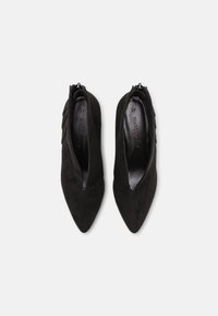 Botines de ante negro con tacón, punta afilada y cierre de cremallera lateral. Presenta un acento texturizado a lo largo del tacón. Talla 37.