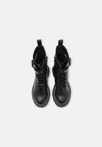 Botas de tobillo de cuero negro con punta redonda, cordones en la parte delantera y detalle de hebilla. Suela texturizada y tirador en la parte posterior para facilitar su uso.