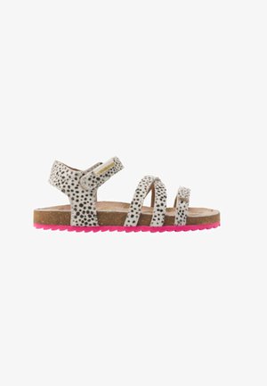 Weiße Sandale mit schwarzen Punkten, ausgestattet mit drei Riemen und einem Klettverschluss. Braune Fußbett und rosa Gummisohle mit strukturiertem Muster.