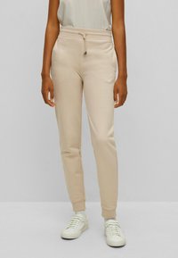 Beige Sweatpants aus weichem Stoff, mit einem elastischen Bund und Kordelzug, schmal zulaufenden Beinen und gerippten Bündchen. Mit einem kleinen Logo akzentuiert.