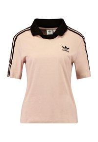 Pikétröja i ljusrosa tyg med en svart krage. Har svarta tre-rands accenter på ärmarna och en broderad svart logotyp.