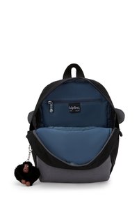 Rugzak met een zwarte buitenkant en een blauwe binnenkant, voorzien van een ritsvak en een harige aap-sleutelhanger eraan bevestigd.