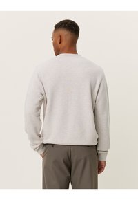 Felpa grigia con collo rotondo e maniche lunghe, caratterizzata da una vestibilità comoda e polsini a costine. Colore semplice e uniforme, texture morbida.