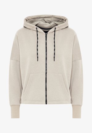 Beige krēklā ar rāvējslēdzēju, izgatavots no mīkstas kokvilnas auduma, ar kapuci ar auklu, lielām priekšējām kabatām, ribotām aprocēm un kontrastējošu melnu rāvējslēdzēju.