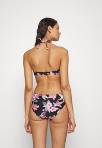 Juodas gėlių bikini komplektas su halterio tipo viršumi, surišamu kaklo ir nugaros srityse, papuoštas rožinėmis ir žaliomis gėlių raštais abiejuose gabaluose.