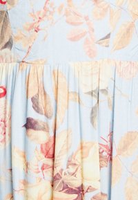 Látka s květinovým vzorem s pastelovými barvami na světle modrém pozadí; skládání textury s listy a okvětními lístky v jemných odstínech.