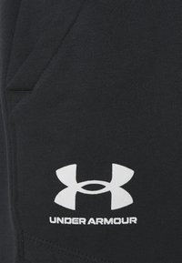 Svarta träningsbyxor i en bomullsblandning, med en sidoficka och vit "Under Armour"-logotyp på den nedre delen av benet.