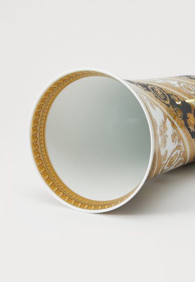 Ceramiczny kubek o błyszczącej czarnej powierzchni z misternymi złotymi wzorami i białymi akcentami. Gładka wewnętrzna powierzchnia, szeroki, okrągły otwór.