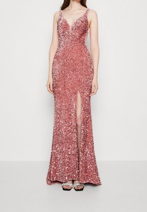 Woman wearing a sleeveless, deep V-neck pink sequin gown with a high front slit, paired with black square-toe sandals with decorative straps.