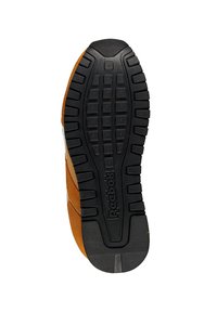 Suela de zapatilla Reebok con un patrón de goma negra y texturizada, con cuadrados elevados y un logo, complementada por un diseño superior de ante marrón y beige.