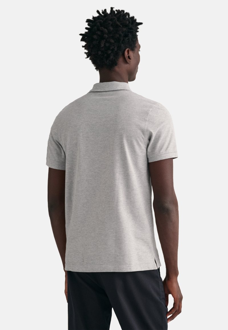 Szara koszulka polo wykonana z miękkiego materiału, z kołnierzykiem, krótkimi rękawami oraz bocznymi rozcięciami na hemie dla swobody ruchów.