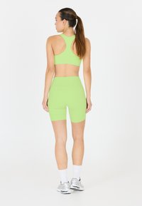 Neongrön sportbehå och matchande högmidjade shorts gjorda av stretchigt material, med racerback-design och slät textur.