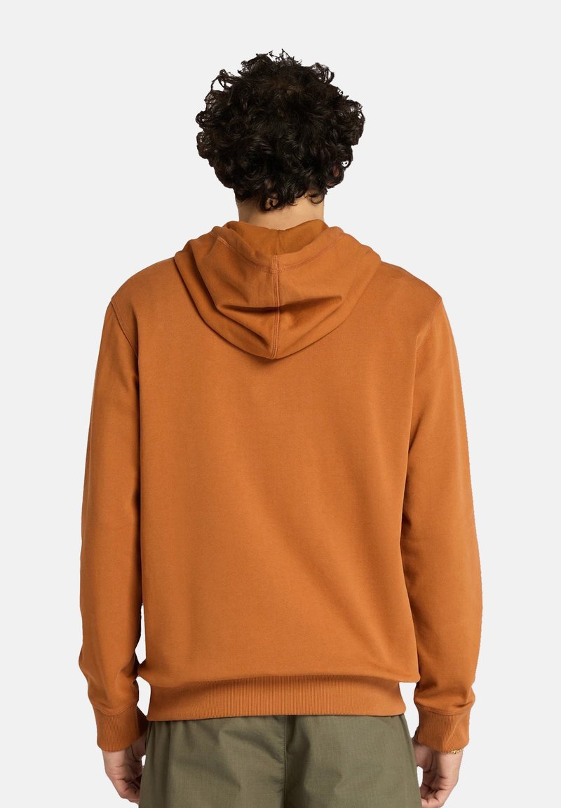 Sweat à capuche en orange rouille, fabriqué en tissu doux, avec des poignets et un ourlet côtelés, dotée d'une couture centrale dans le dos et d'une coupe ample.