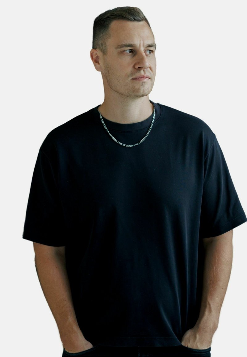 Sort kortærmet t-shirt i bomuldsblanding med en afslappet pasform, rund hals og subtil struktur, accessoriseret med et sølv kædevedhæng.