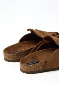 Sandali slip-on in suede marrone con suole in sughero e etichette blu "Piombo" visibili all'interno della soletta, mostrati su uno sfondo bianco.