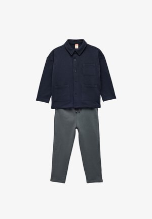 Camicia azzurra con bottoni, colletto e due tasche frontali, abbinata a pantaloni grigi con vita elastica. Entrambi i capi sono realizzati in un tessuto morbido.