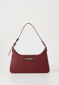 Rote Ledertasche mit geschwungener Form und kurzem Schulterriemen. Mit silberner Logoplatte auf der Vorderseite. Strukturierte Oberfläche.