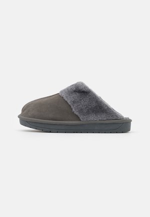 Chausson gris à enfiler avec doublure en polaire moelleuse et dessus en daim, équipé d'une semelle en caoutchouc noir pour une utilisation intérieure ou extérieure.