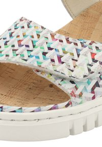 Sandales tissées avec un motif géométrique multicolore sur une base blanche, dotées d'une semelle intérieure en liège et d'une épaisse semelle blanche.