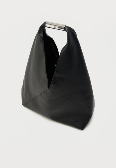 Črna usnjena torba za na ramo z unikatnim V-obliki, z metalnim ročajem in teksturirano površino. Spodaj ima ravno podlago za stabilnost.