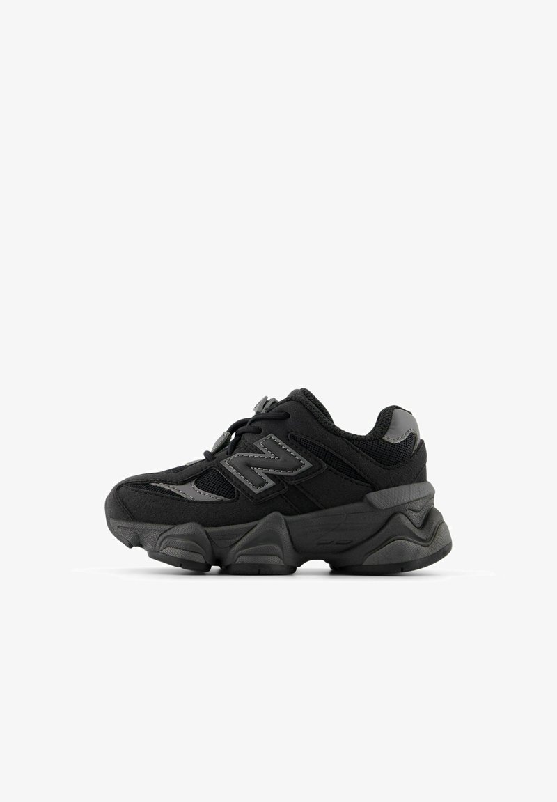 Baskets noires New Balance avec semelle épaisse, panneaux en mesh et daim, accents réfléchissants et fermeture à lacets, vues de profil.