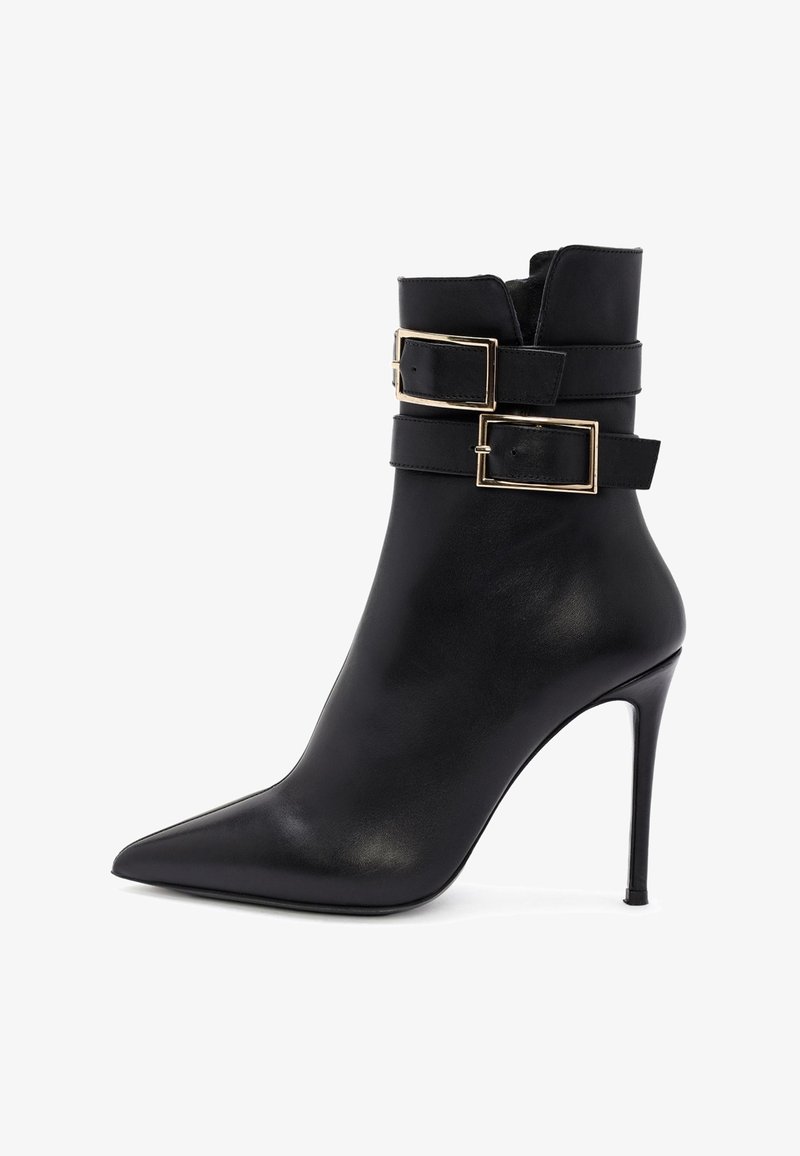 Bottine noire en cuir à bout pointu avec talon aiguilles et deux sangles décoratives avec boucles rectangulaires dorées.