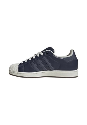 Sneaker bassa blu navy con punta in gomma bianca, lacci bianchi, tre strisce laterali e suola bianca.