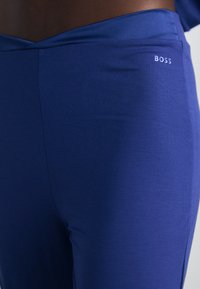 Mėlynos legginsai iš tamprių audinių, su sulenkta liemene ir subtiliu baltu "BOSS" logotipu kairėje pusėje. Lygus paviršius.