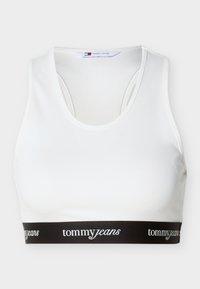 Λευκό αθλητικό σουτιέν με μαύρη ελαστική ταινία στο κάτω μέρος που φέρει επαναλαμβανόμενο λευκό κείμενο "tommy jeans".